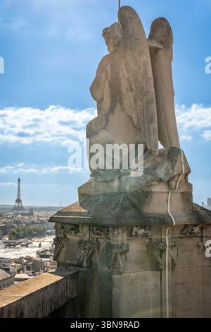 Parigi, Francia - 06 28 2025: Veduta dettagliata di uno dei simboli scolpiti della statua dei quattro evangelisti, l'angelo Matteo e la Torre Eiffel dietro Foto Stock
