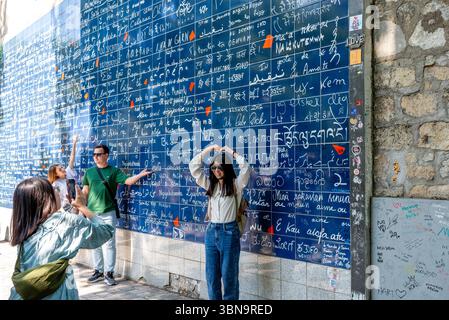 Turisti che scattano foto di fronte al muro di "i Love You" a Montmartre. Il muro è presente anche nella serie Netflix "Emily in Paris" Foto Stock