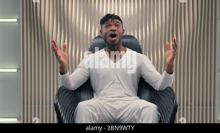 Cyber-uomo afroamericano stupito sorpreso dicendo Wow reazione sorprendente guardare la telecamera meraviglia buone notizie in studio futurismo bianco indoor videogamer maschile Foto Stock