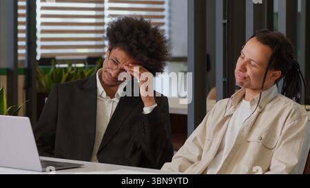 Due uomini afroamericani uomini d'affari colleghi disperatamente stressati uomini d'affari preoccupati colleghi che lavorano insieme computer portatile Internet in ufficio online Foto Stock