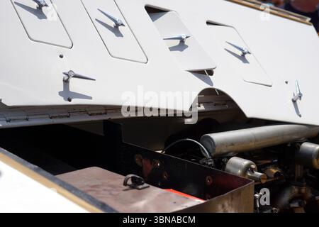 Cipro, Larnaca, Una vista ravvicinata della parte inferiore di un'auto d'epoca, forse un'auto d'epoca. La carrozzeria della vettura è principalmente bianca, con alcune aree marrone scuro o nere, e presenta una serie di piccole aperture o scomparti rettangolari. Queste aperture sono fissate con cerniere in metallo color argento o cromato. Il motore della vettura è visibile, con una grande componente cilindrica argento e un componente più piccolo di colore scuro. Il motore è parzialmente oscurato dalla carrozzeria della vettura. La carrozzeria della vettura è inoltre dotata di alcuni piccoli rivetti o bulloni di colore scuro visibili. La carrozzeria dell'auto si appoggia su un colore scuro Foto Stock