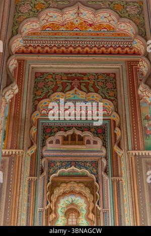 Archi colorati adornati da intricati motivi floreali creano una prospettiva affascinante all'interno di un edificio tradizionale a Jaipur, che riflette la regione Foto Stock