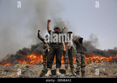 I soldati DELLA DISTRUZIONE DI NARCOTICI DELLO YEMEN stanno di guardia vicino a una pila di droghe confiscate mentre bruciano e cantano slogan, a Sanaa, Yemen, 1° luglio 2025. Le forze di sicurezza affiliate agli Houthi hanno incenerito e distrutto grandi quantità di narcotici sequestrati durante le incursioni contro i contrabbandieri in varie regioni dello Yemen dalla metà del 2024. Secondo una dichiarazione delle autorità Houthi-run, le sostanze distrutte includevano oltre 18 tonnellate di hashish, più di 205.000 pillole di Captagon e 12,3 milioni di compresse di pregabalin. IMAGO/ Sanaa Yemen Copyright: XHamzaxAlix Foto Stock