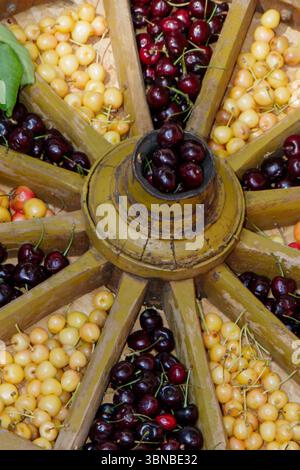 Una varietà di ciliegie e frutti di bosco sono disposti ad arte in un modello circolare presso una banchina del mercato. Foto Stock
