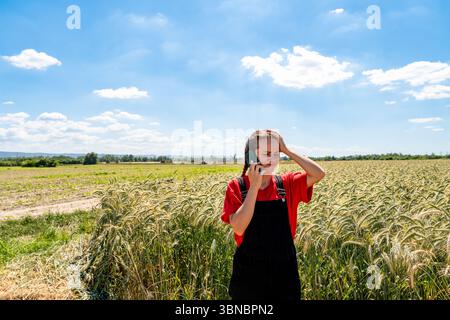 Donna agricoltrice che riceve cattive notizie durante una telefonata dal campo dei cereali Foto Stock