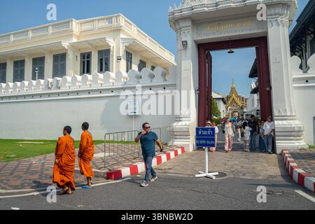 I turisti che escono, i monaci passano davanti a un cancello in uno storico Grand Palace, il complesso del Palazzo reale a Bangkok, Thailandia. Foto Stock