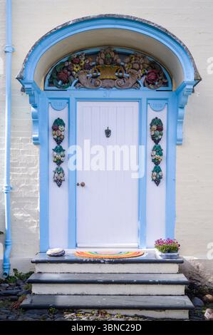 L'elegante e eccentrica porta dipinta di blu e bianco luminoso nel famoso e iconico villaggio di Clovelly con tradizionale proprietà d'epoca vicino a Bideford nel Devon Foto Stock
