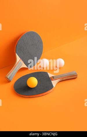 Racchette da ping pong e palline su sfondo arancione Foto Stock