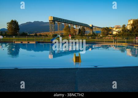 Nuova piscina di Brighton presso il New Brighton Park di Vancouver, British Columbia, con ascensore per cereali, secondo ponte Narrows e North Shore Mountains dietro. Foto Stock