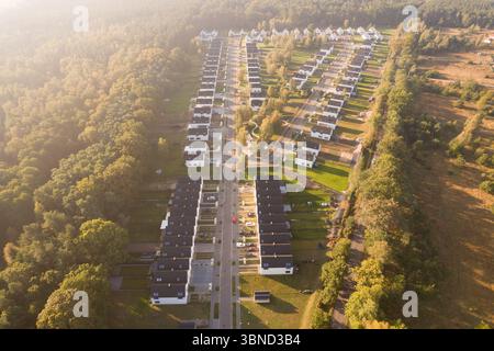Vista aerea di un moderno complesso residenziale con case bianche identiche situate accanto a una foresta verde. Il quartiere residenziale è immerso nella Foto Stock