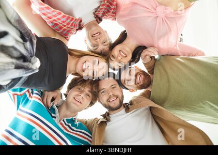 Gruppo di amici, persone in piedi insieme a formare un cerchio che guarda in basso sorridente felice Foto Stock