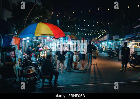 Tradizionale mercato di cibo notturno a Wonosobo, Giava centrale, Indonesia - le persone esplorano bancarelle di cibo di strada sotto le luci festose in una serata vivace. Foto Stock