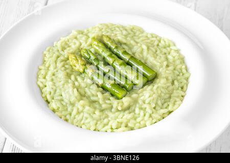 Risotto cremoso con punte di asparagi verdi, guarnito e presentato splendidamente Foto Stock