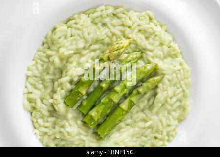 Risotto cremoso con punte di asparagi verdi, guarnito e presentato splendidamente Foto Stock