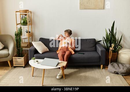 Una donna accogliente si gode una bevanda calda, assaporando un momento di pace a casa. Foto Stock