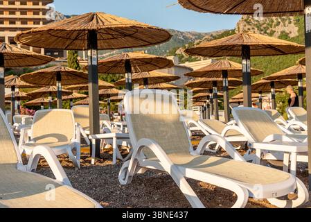 Bar, Montenegro, 23 giugno 2025, spiaggia attrezzata di ciottoli sul mare Adriatico, lettini vuoti al tramonto Foto Stock