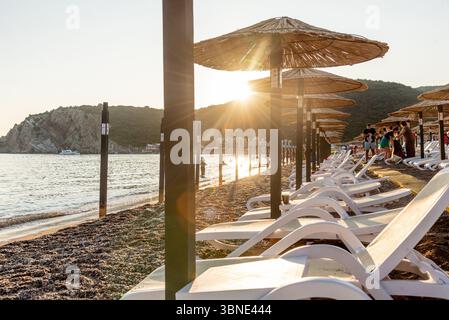 Bar, Montenegro, 23 giugno 2025, spiaggia attrezzata di ciottoli sul mare Adriatico, lettini vuoti al tramonto Foto Stock