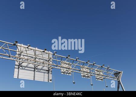 Linea di traffico sopra l'autostrada con più sensori per il controllo della velocità e la registrazione della targa, che simboleggiano l'infrastruttura moderna e la topografia Foto Stock