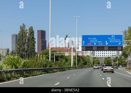 autostrada A12 entrando a l'Aia, con cartelli chiari per le destinazioni, che mostrano i viaggi urbani e le infrastrutture sotto un cielo blu. Foto Stock