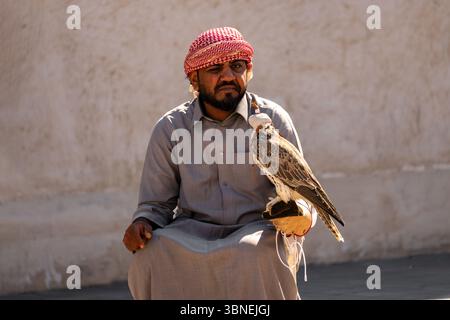 DOHA, QATAR 2 febbraio 2025. Un falco per mano di un uomo arabo in abiti tradizionali nazionali. Il concetto di falconeria. il commercio di falchi nel falco Foto Stock