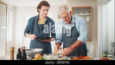 Uomini, chef o cucina con tablet in cucina per abilità culinarie o ospitalità a casa. Maturo, mentore e aiutante la persona con la tecnologia o. Foto Stock