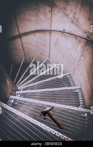 Scala metallica a spirale con un martello macchiato di sangue steso sui gradini, evocando un senso di mistero, violenza e un crimine irrisolto Foto Stock