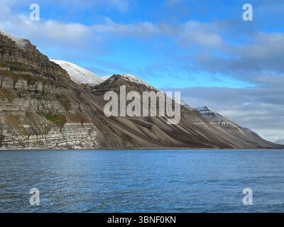 Una splendida vista su una catena montuosa vicino a un lago calmo sotto un cielo blu, Spitsbergen, Svalbard Foto Stock