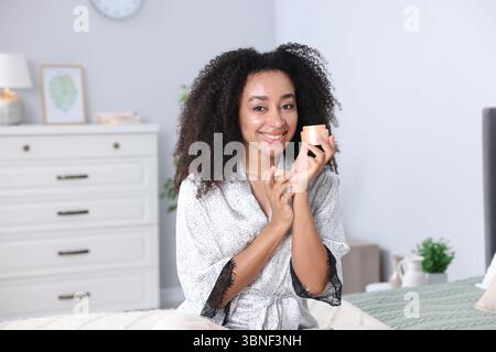 Bella donna brasiliana con barattolo di crema al collagene al chiuso Foto Stock