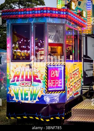 Biglietteria colorata per il carnevale con luci al neon che offre giostre in una fiera divertente durante la notte. La città di Hoppings ormeggia a newcastle Foto Stock