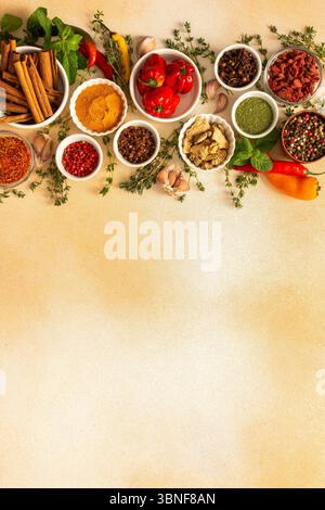 Una variopinta gamma di spezie secche ed erbe fresche disposte su un morbido sfondo beige, ideale per condire e aggiungere un ricco sapore ai piatti, vista dall'alto, Foto Stock