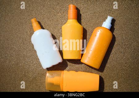 Bottiglie in tubetto di crema per la pelle sulla spiaggia sabbiosa. Contenitori di lozione in plastica sulla spiaggia tropicale per i concetti di idratazione della pelle. bottiglia di crema solare senza marchio Foto Stock