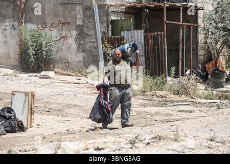 Tulkarm, Palestina. 2 luglio 2025. Un palestinese porta i propri effetti personali mentre fugge dal campo profughi di Tulkarm. Le forze israeliane hanno permesso ai residenti di recuperare i loro effetti personali dopo aver emesso avvisi di demolizione per diverse case, nel mezzo di un'offensiva durata mesi in Cisgiordania che ha allontanato circa 35.000 palestinesi dalle loro case nel campo profughi di Tulkarm. Credito: SOPA Images Limited/Alamy Live News Foto Stock