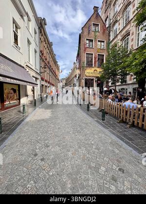 Stretta strada acciottolata fiancheggiata da caffetterie e facciate storiche nel centro di Bruxelles, Belgio. Foto Stock