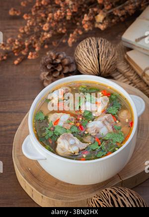 Una tradizionale zuppa thailandese con teneri ossa di maiale bollite in un ricco brodo speziato, guarnite con coriandolo fresco e peperoncino. Perfetto per chi Foto Stock