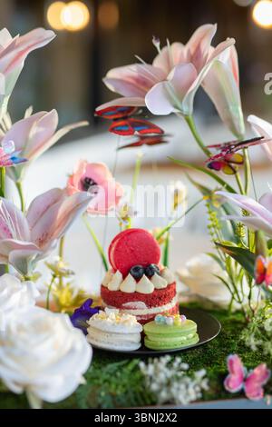 Una deliziosa fetta di torta di velluto rosso con strati cremosi di crema di formaggio liscio, splendidamente guarnita con fiori a margherita viola. Foto Stock