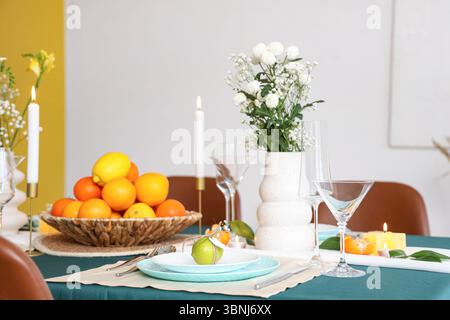 Splendido tavolo con agrumi sul piatto e fiori in vaso. Primo piano Foto Stock