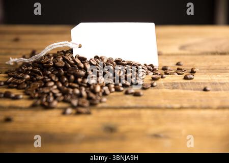 Rendering 3D che mostra un mucchio di chicchi di caffè tostati su un tavolo rustico con tag vuoto, stringa bianca Foto Stock