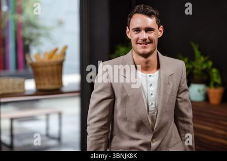 I cesti di vimini che contengono baguette fresche sono seduti nel caffè su un banco di legno, accanto alle piante in vaso Foto Stock