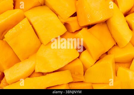 Una vista ravvicinata dei pezzi di mango appena tagliati, catturando la vivace consistenza arancione del frutto. Questa immagine ad alta risoluzione è ideale per l'uso come sfondo Foto Stock