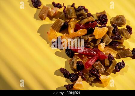 Un vivace assortimento di frutta candita e secca, tra cui ciliegie, rabarbaro e cotogna, sparsi su uno sfondo giallo brillante. Perfetto per una guarigione Foto Stock