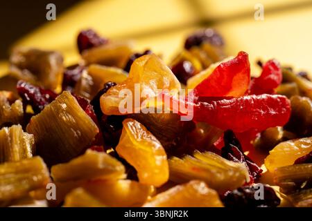 Un variopinto assortimento di frutta candita e secca, tra cui ciliegie, rabarbaro e cotogna, disposti ad arte su uno sfondo giallo brillante. Perfetto f Foto Stock