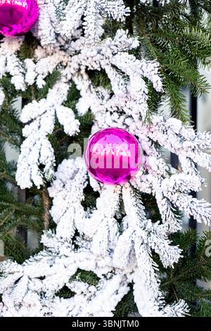 Una splendida corona di Natale adornata da vivaci baule rosa e rami smerigliati. Gli aghi di pino verde contrastano con l'effetto nevoso, creando un Foto Stock