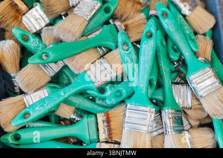 Una collezione di pennelli da pittura in un vivace laboratorio di creazione di maschere a Venezia. Strumenti con manici verdi pronti per creare intricate maschere veneziane in una cre Foto Stock