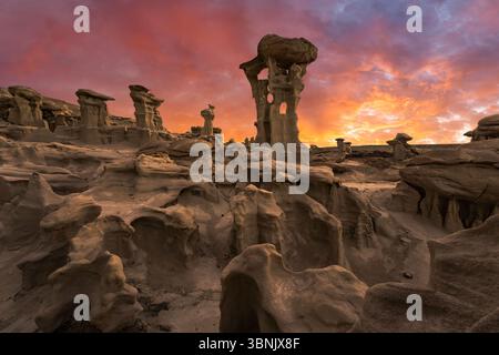 Spettacolari formazioni rocciose nella riserva naturale di Bisti/De-Na-Zin, New Mexico, sotto un vibrante cielo al tramonto. Il paesaggio arido mette in mostra la bellezza unica Foto Stock