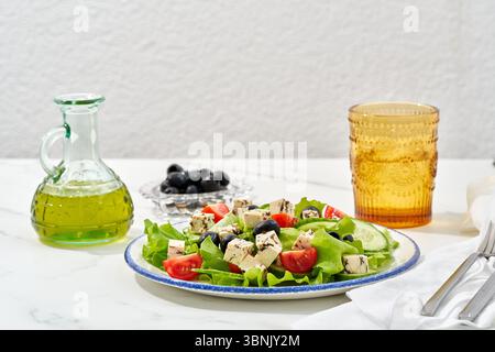 Una vivace insalata vegana con cubetti di tofu, lattuga fresca, pomodori ciliegini e olive nere, condite con olio d'oliva. Perfettamente rinfrescante per un'ora Foto Stock
