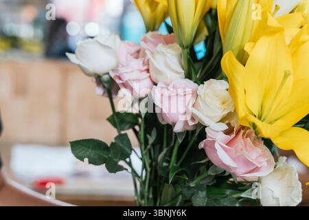 Un vivace bouquet di rose rosa e bianche con gigli gialli esposti in un negozio fioraio di Bali. La disposizione lussureggiante mostra la bellezza e l'eleganza Foto Stock
