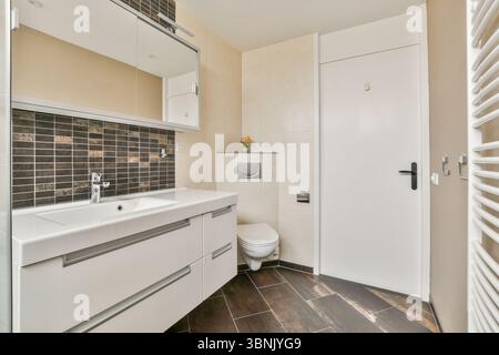 Un bagno contemporaneo con mobili eleganti, piastrelle eleganti e finiture moderne, che offrono funzionalità e fascino estetico Foto Stock
