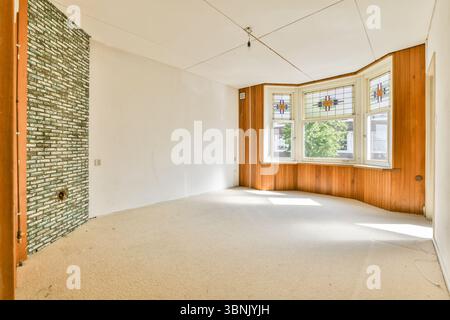 Una sala luminosa e spaziosa, caratterizzata da eleganti vetrate colorate e da un'affascinante finestra a bovindo, offre un'atmosfera intima con abbondante luce naturale. Foto Stock