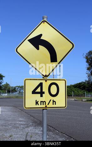 Svolta a sinistra e i segnali del limite di velocità sono montati su un singolo polo accanto a una strada Foto Stock