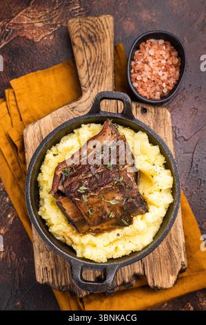 Primo piano di teneri costolette di manzo, splendidamente caramellate e riposate su un letto di cremoso purè di patate, creando un'invitante scena culinaria. marrone Foto Stock